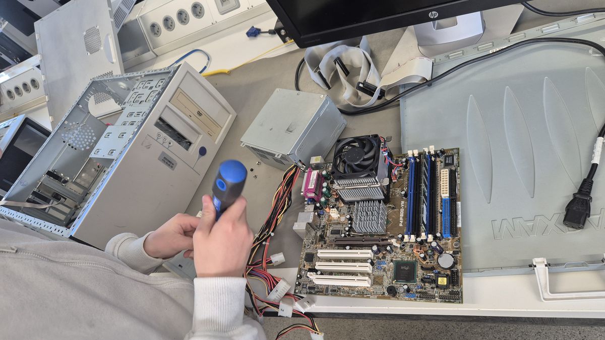 Schüler baut einen PC zusammen und schraubt am Mainboard