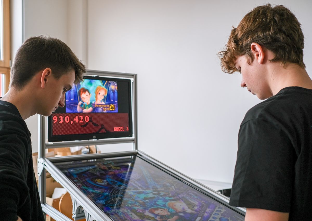 Zwei Schüler am digitalen Flippertisch mit Highscore-Anzeige